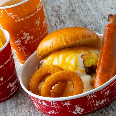 グラタン仕立てのアボカドチーズバーガー、骨付きソーセージとオニオンリング添え